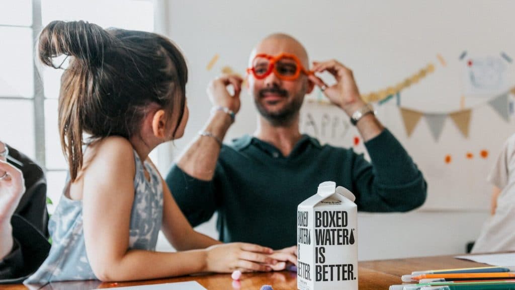 a man and a little girl sitting at a table with a milk carton